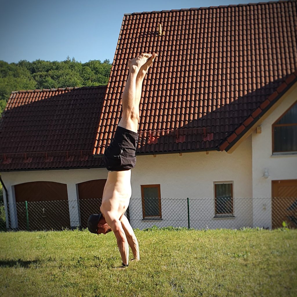 Mann Daniel macht freistehenden Handstand.